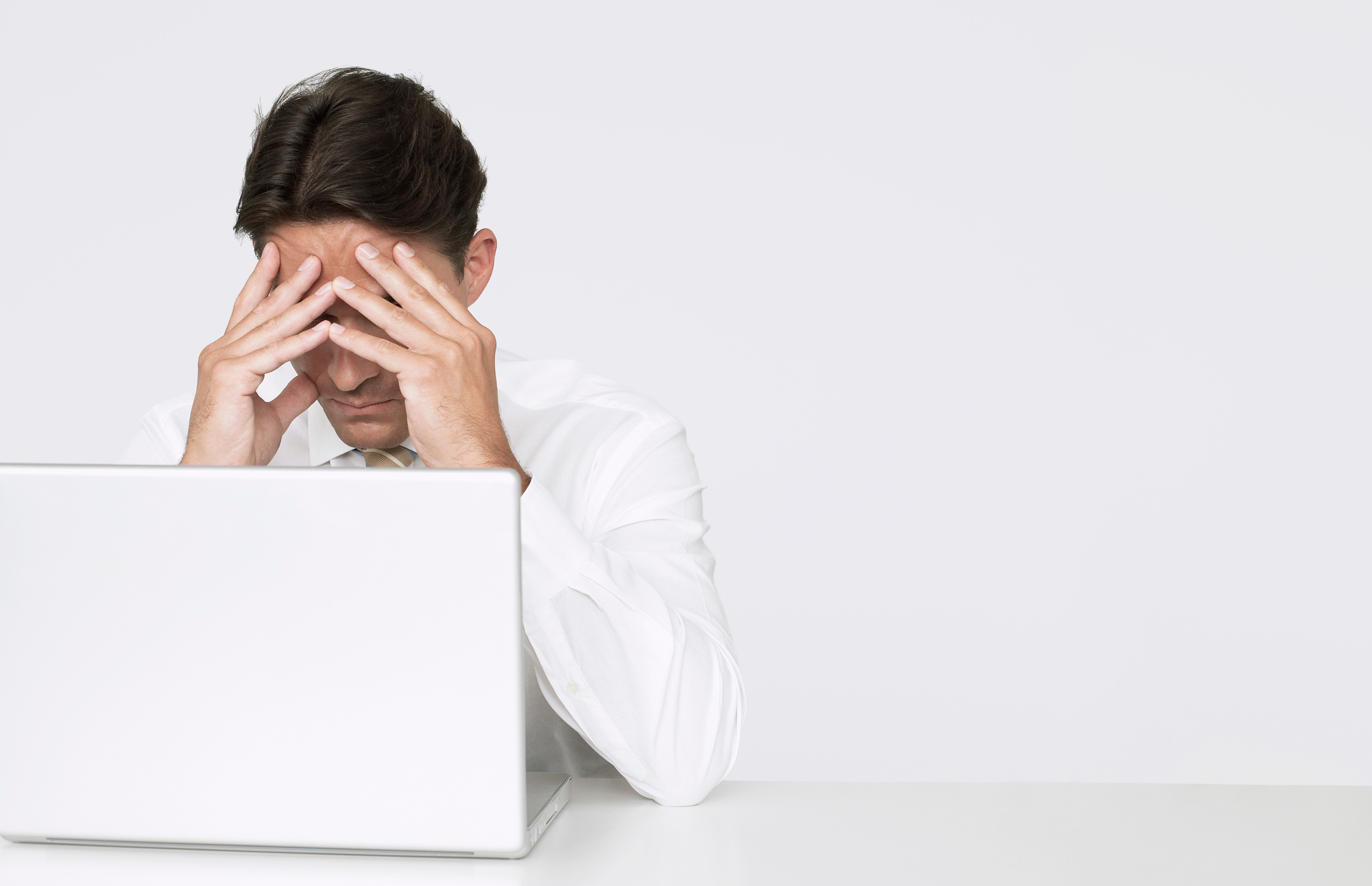 Businessman with head in hands in front of laptop